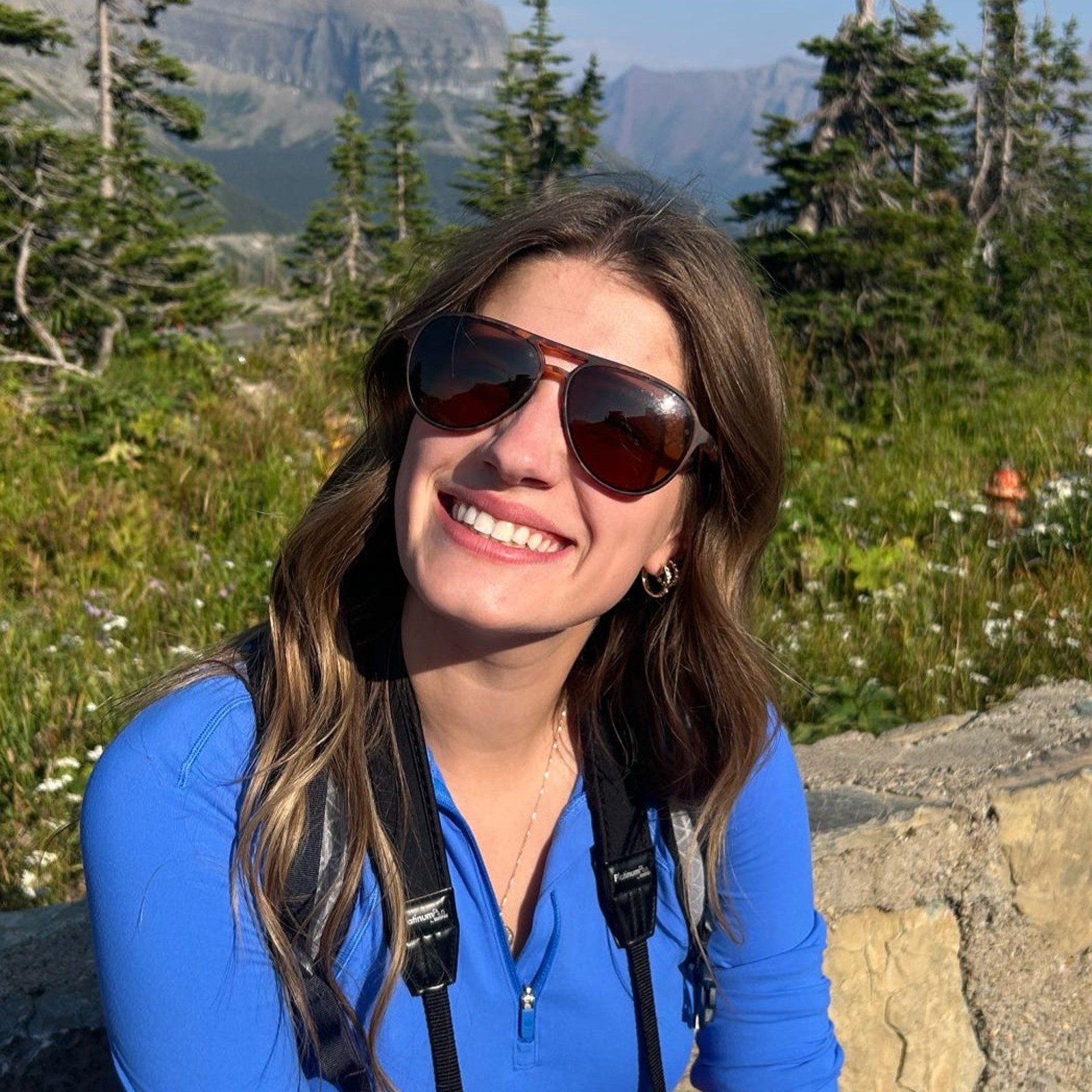FLBS Marketing Intern Ellie Erickson smiles in front of Glacier National Park mountains