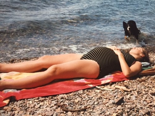 Pregnant woman sunbathing on beach, Ginny Miller