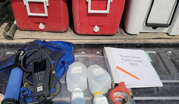Three coolers (two red and one white), flow meter, monitoring bottles, tape, and book of standard operating procedures 