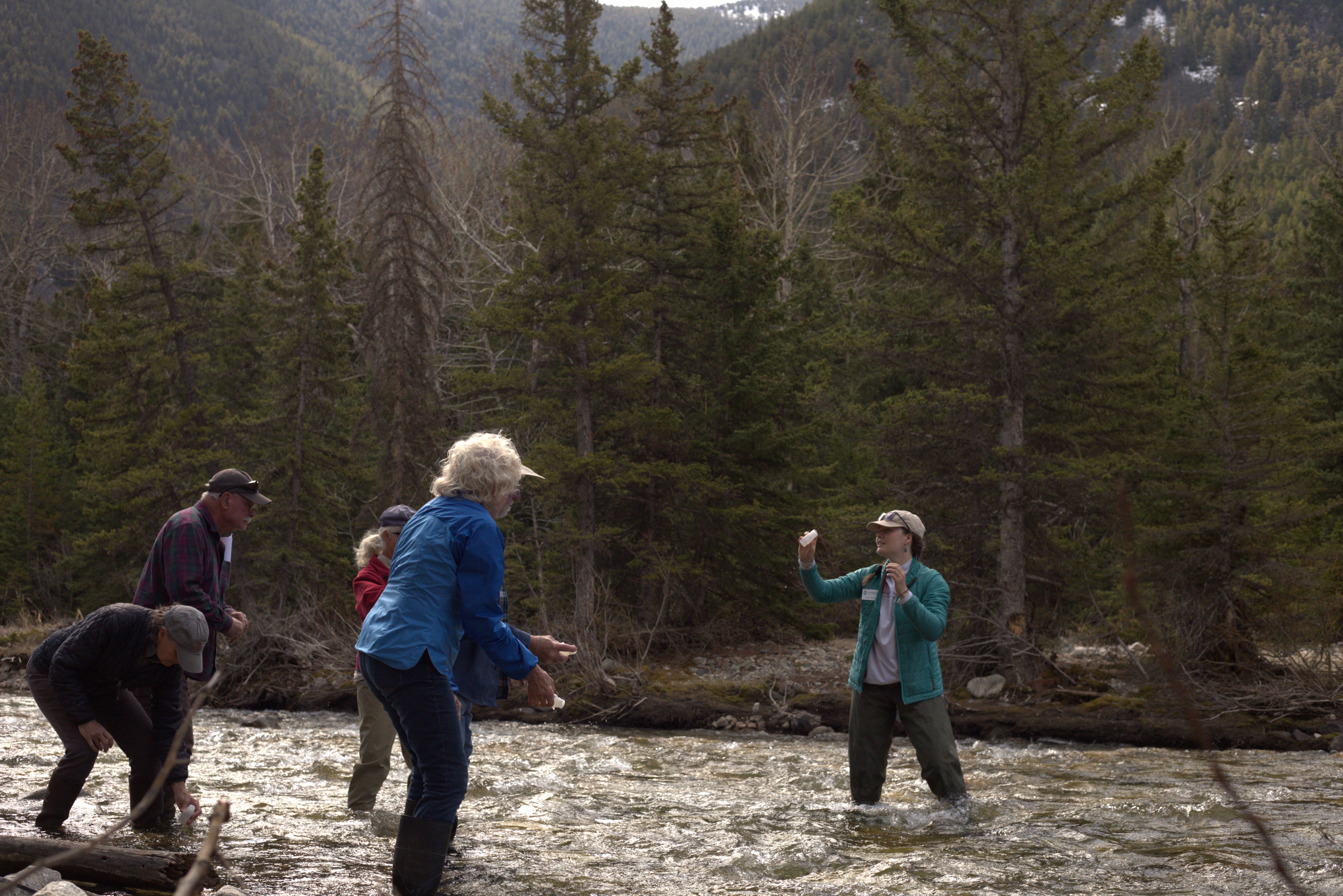 Carbon County Resource Council volunteers are in a stream practicing collecting water samples.