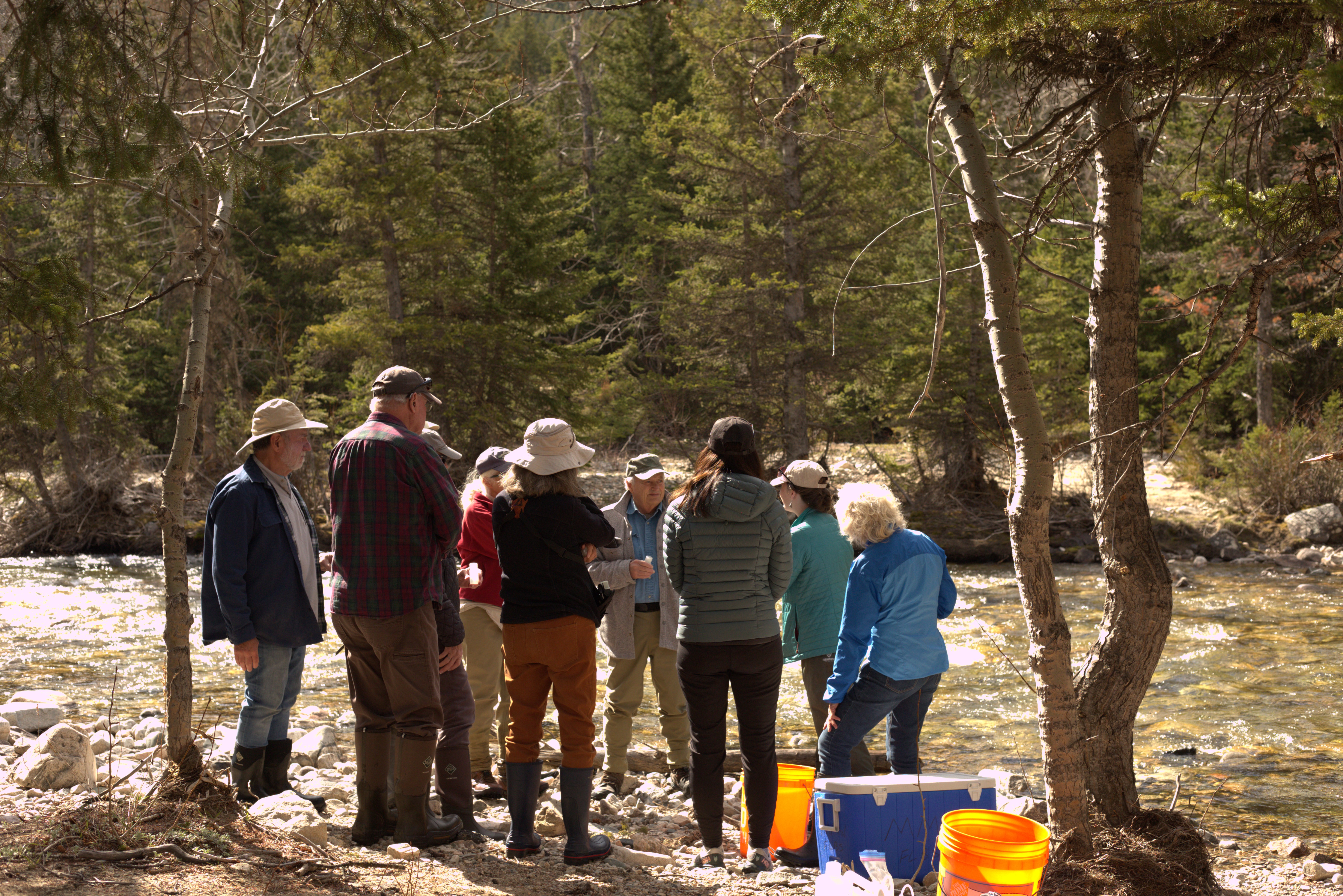 Callie Nelson huddled in a circle with Carbon County Resource Volunteers teaching the group how to collect water samples.