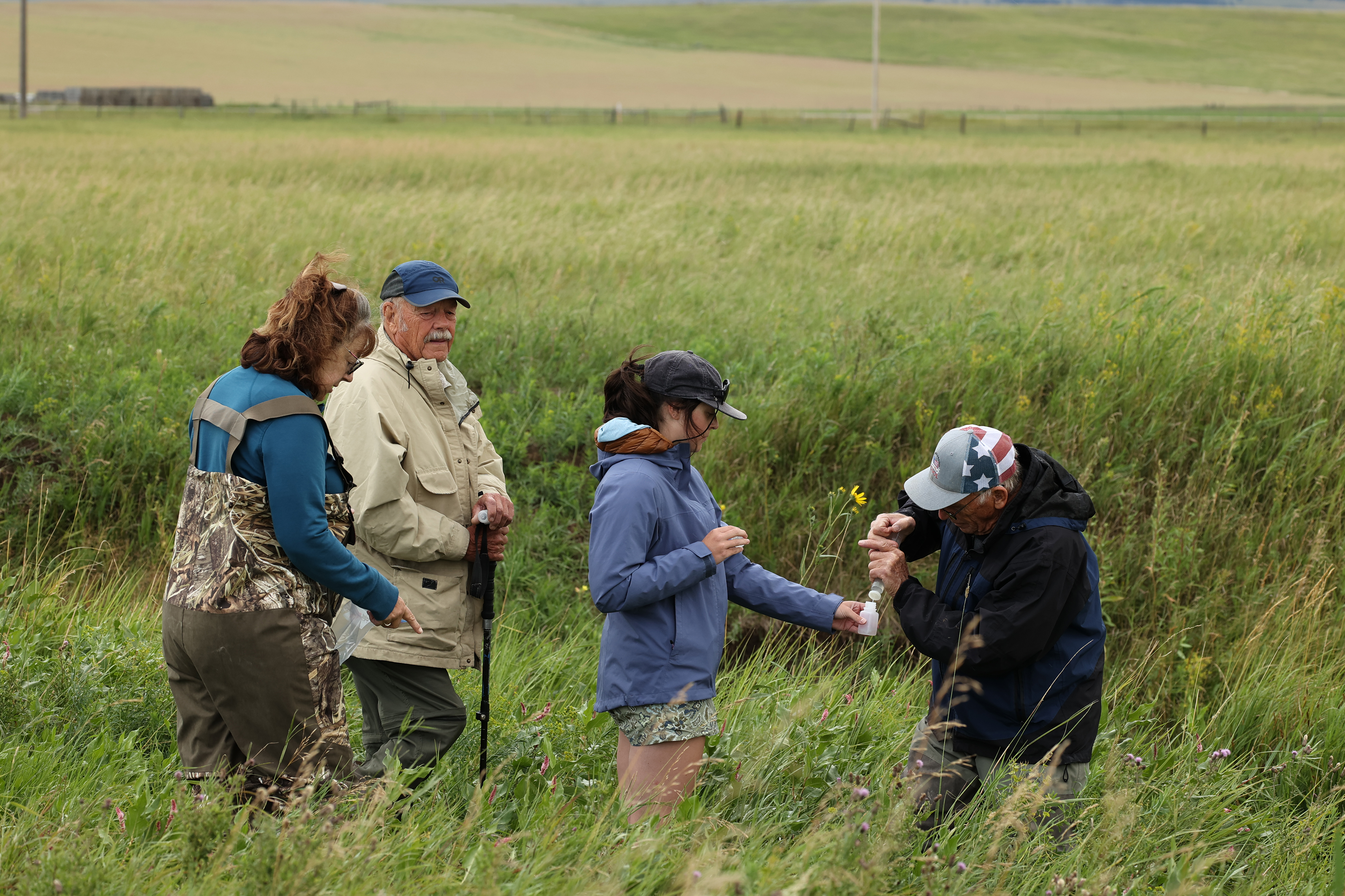 A Big Sky Watershed Corp member collecting a filtered water sample with a Central Montana Resource Council member and showing two other Central Montana Resource Council members how to collected a filtered sample.