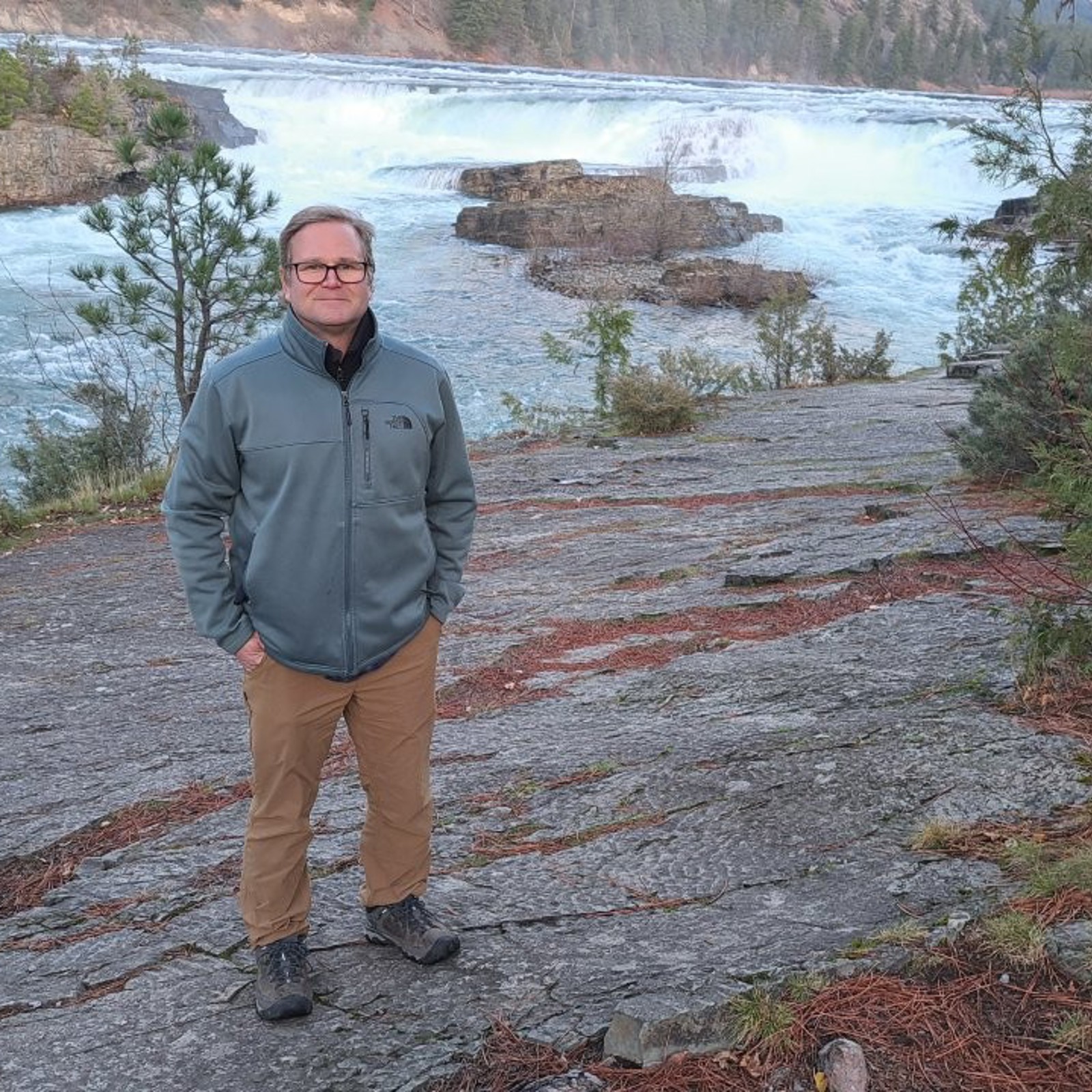 Tom Bansak standing on a rock ledge in front of Kootenai Falls