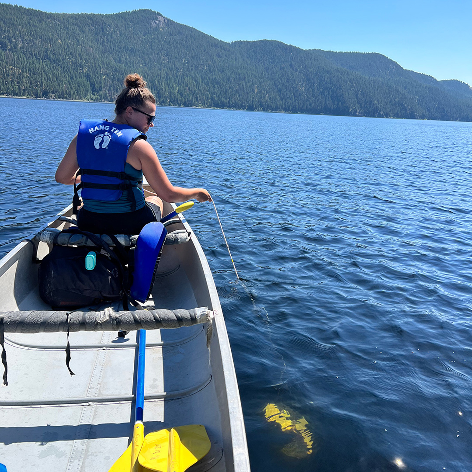 Students lower a water sampler from a canoe in Yellow Bay