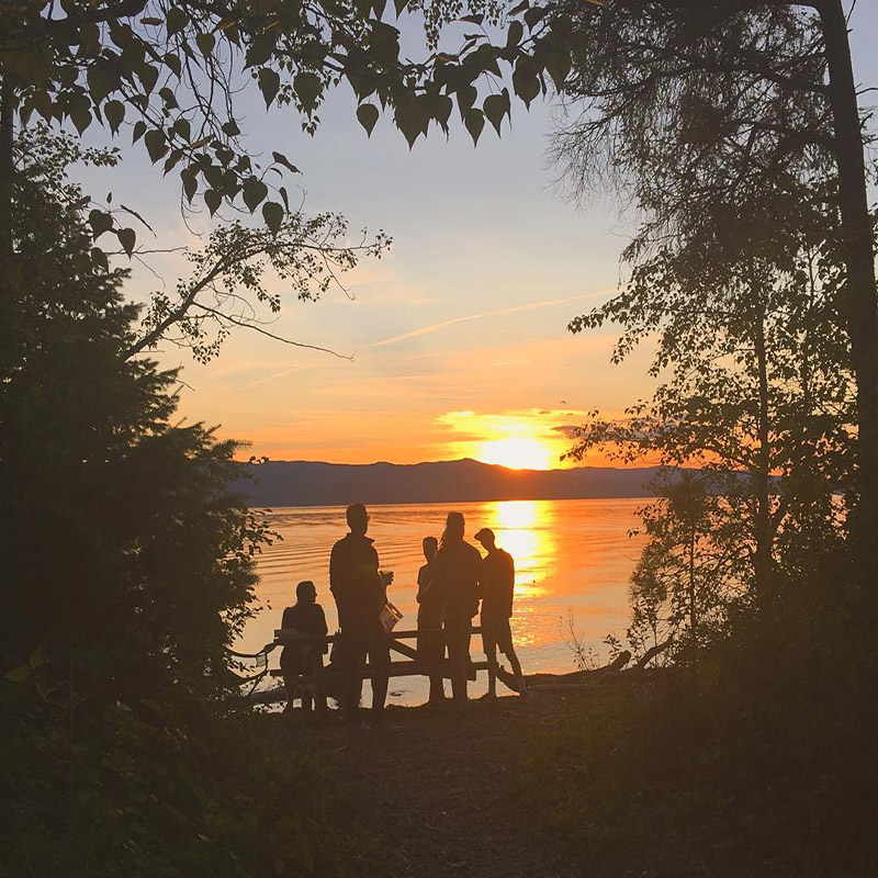 Students gather by the lake at sunset