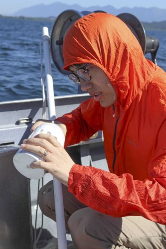 Visiting FLBS Researcher Xiong Xiong examines water sample on Jessie B research boat.
