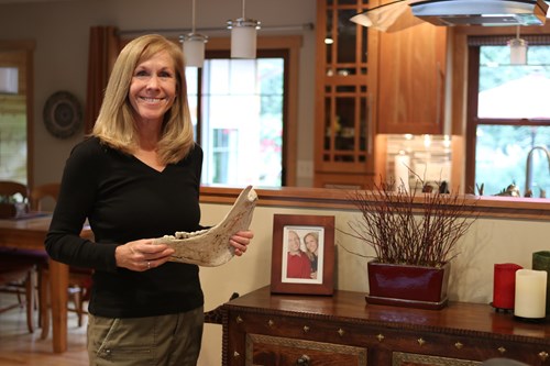 woman poses in her home holding the jaw bone of a horse