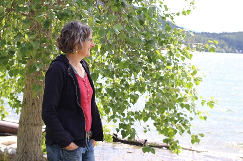 nanette nelson standing by a tree looking out at flathead lake