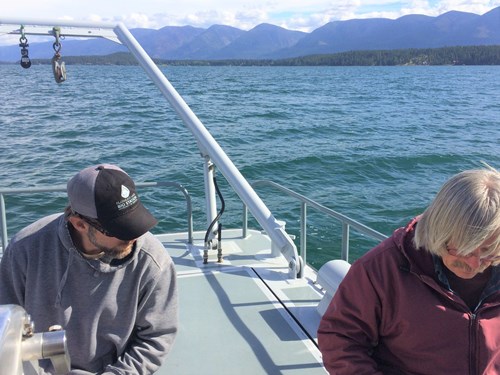 two scientists take readings of water temperature on a boat
