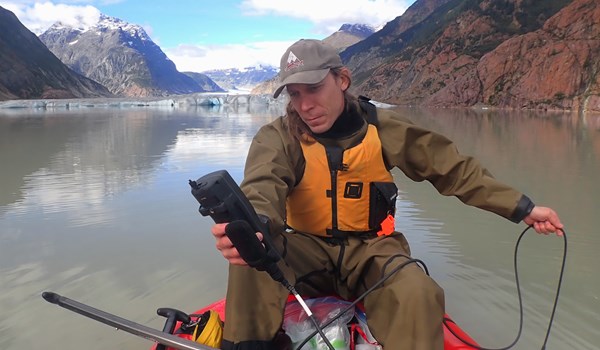 Researcher recording water metrics using a handheld device from a kayak
