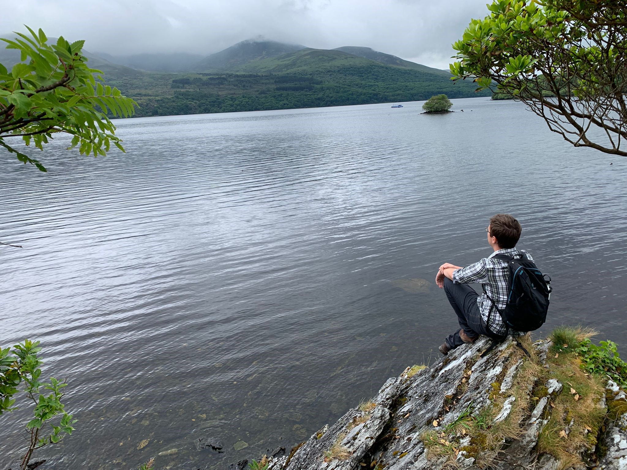 Eliot sitting on a rock coast overlooking a large body of water