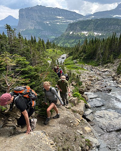 Summer students hike along a creek in Glacier National Park